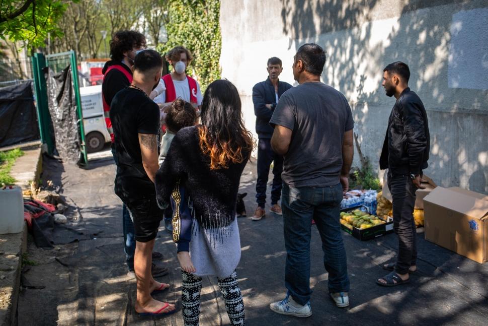 Distribution des paniers repas dans une bidonville Rom à Gentilly. Deux benevoles parlent avec les habitants du bidonville.