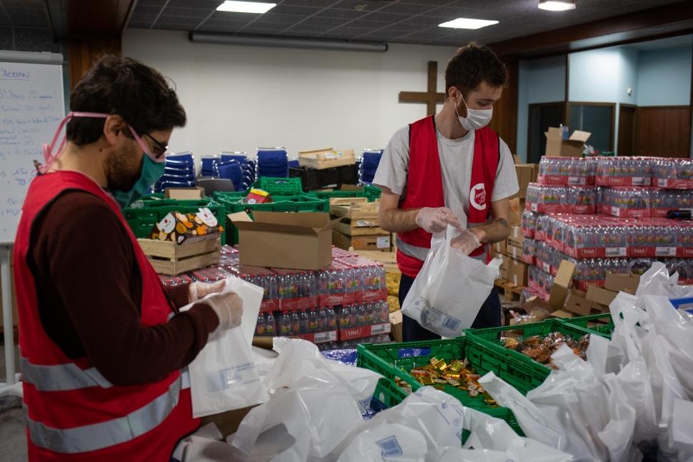 Preparation des paniers repas pour la distribution. dechargement des danrées alimentaires, organisation des panier, constitution des equipes de livraison et chargement des furgons avant livraison. Paniers-repas et kits d’hygiène distribués à Paris