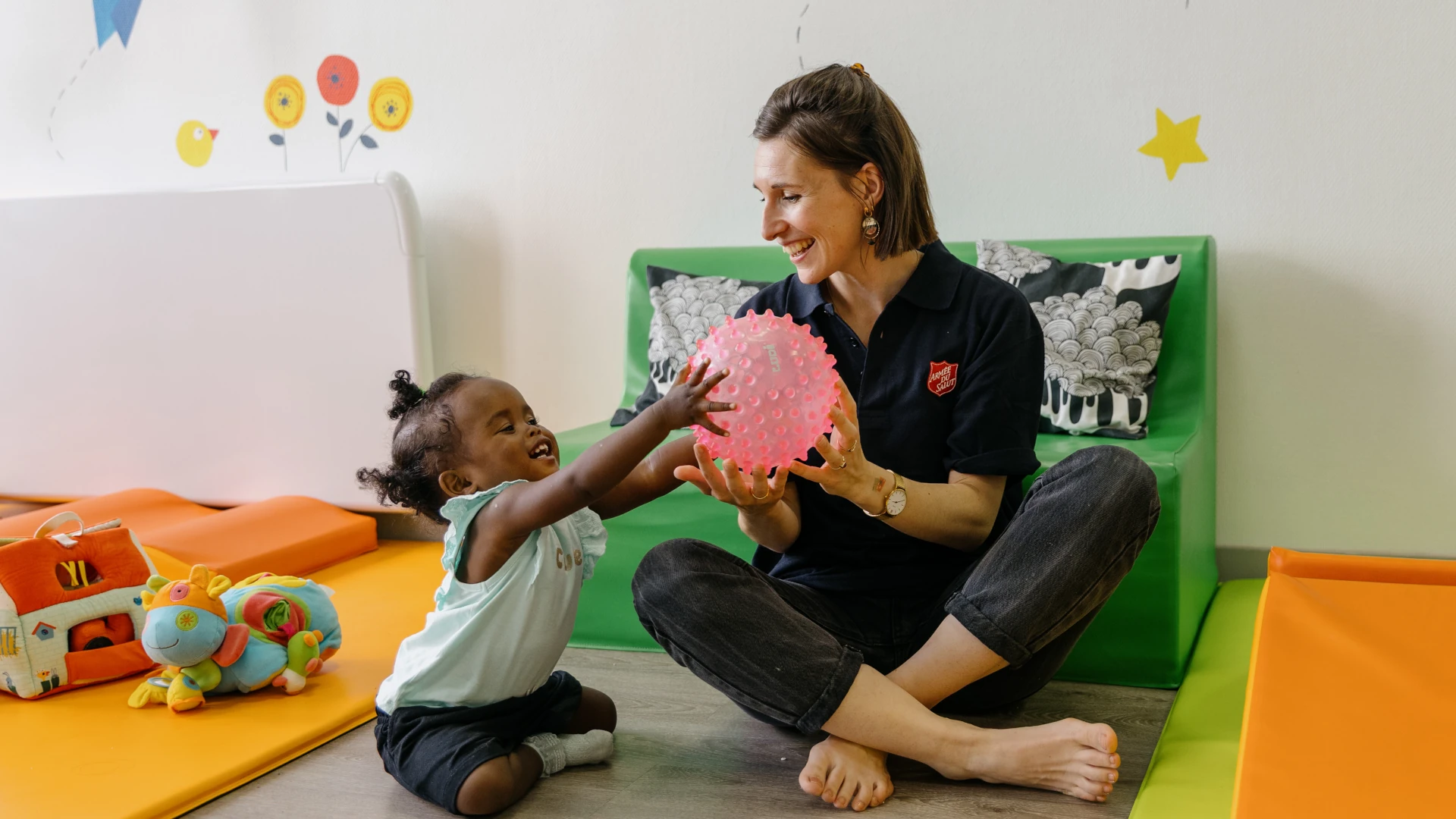 Une salariée de l'Arche de Noé à Lyon joue avec une balle rose que tient dans la main une jeune enfant