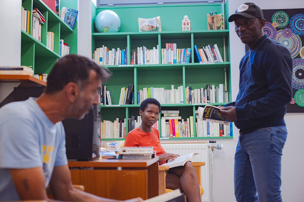Les résidents Milan KIREJ, Marie Claire MUYIZERE et Asset Raoul YAYAT profite d'un temps de lecture et d'échange à la bibliothèque.