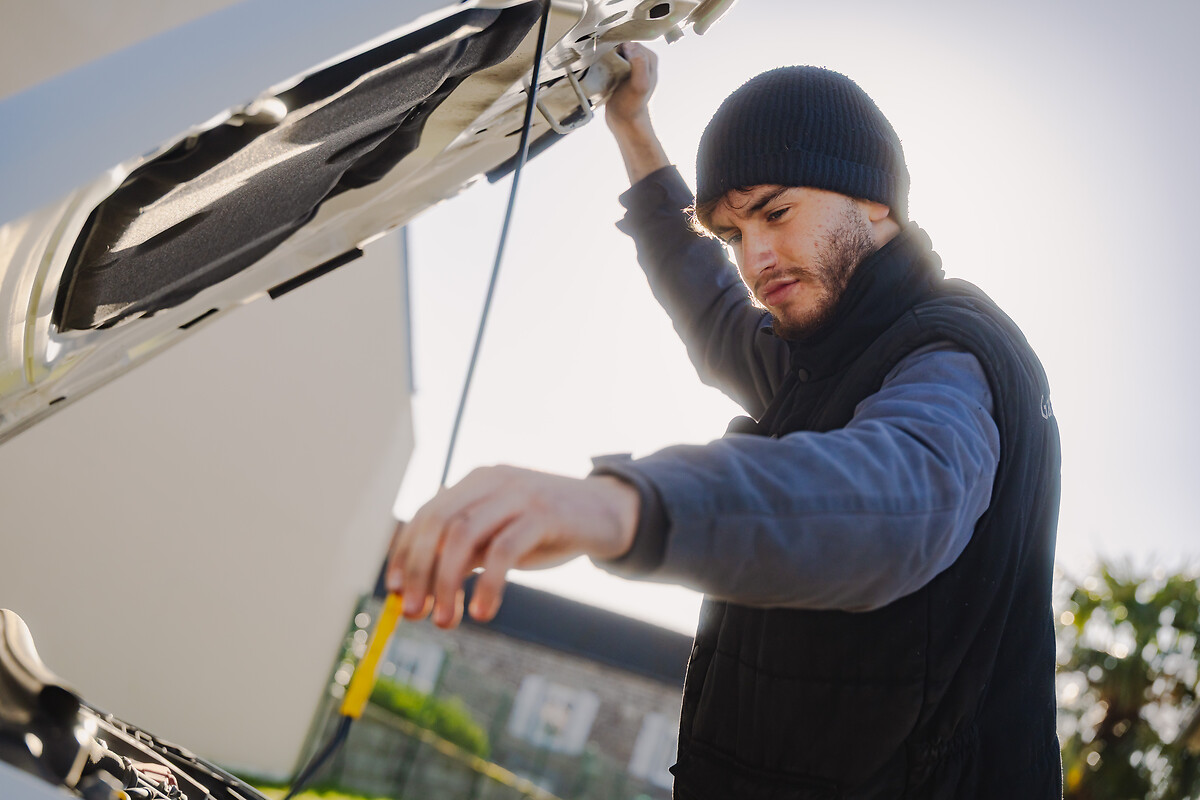 Florjan XHEDIKU au travail. Il change le filtre à air d'une voiture en panne.